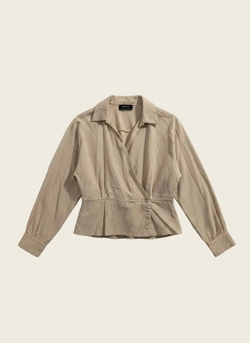 A beige long-sleeve wrap blouse with a pointed collar and a peplum waist, laid flat on a white background.