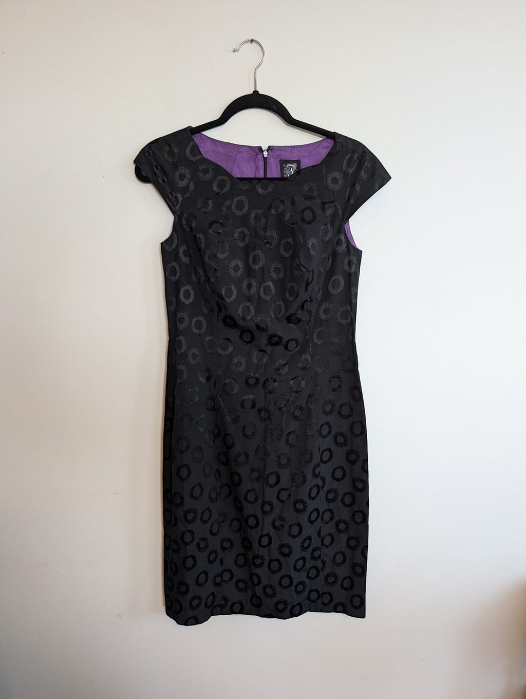 Nu-Nv Clothing black jacquard sheath dress with tonal circle pattern, cap sleeves, and vibrant purple lining.