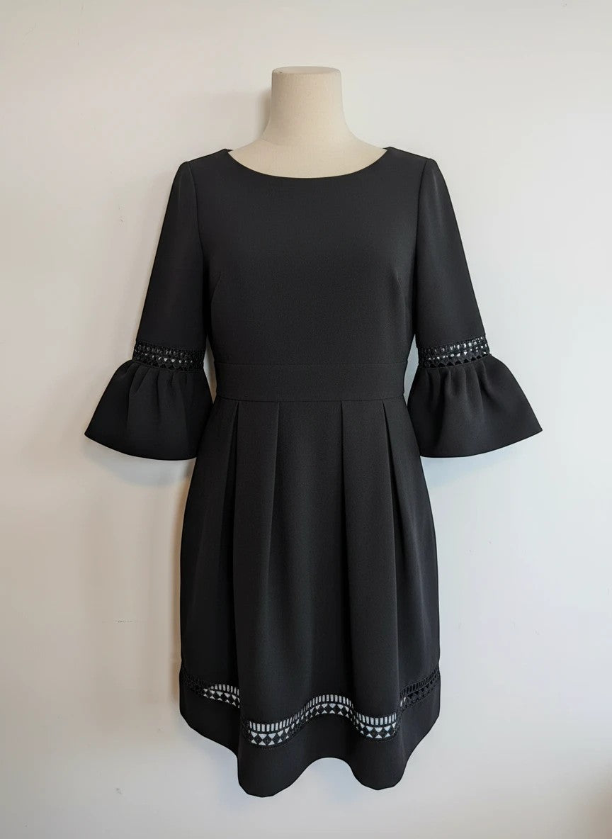 Nu-Nv Clothing black A-line mini dress with pleated skirt, bell sleeves, and intricate lace hem detailing.