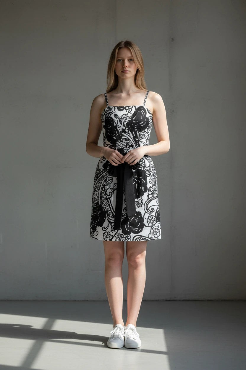Model wearing a Nu-Nv Clothing black and white floral mini dress with square neckline, spaghetti straps, and waist tie