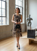 Model wearing a Nu-Nv Clothing brown paisley print sleeveless fit and flare dress with a scoop neckline in a studio.
